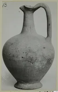 Plain white pottery jug with a tall neck, single loop handle and ring base, photographed against a grey backdrop.