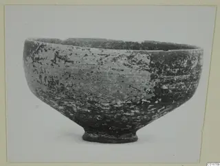Pottery bowl from Marion with a ring foot and mottled, worn surface, shown in side view