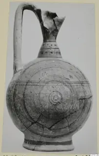 Round-bodied jug with a broken upper neck and handle, decorated with concentric circles and bands, photographed on a plain background.