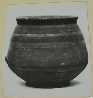 Pottery bowl with a flaring rim, horizontal grooves around the body and a small lug on the left side