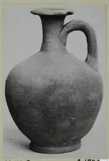 Pottery jug with a flared rim, tall neck and single loop handle, photographed against a plain background.