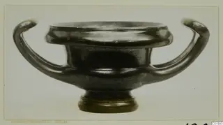 Black glazed two-handled vessel from Marion, seen from the side on a pale background