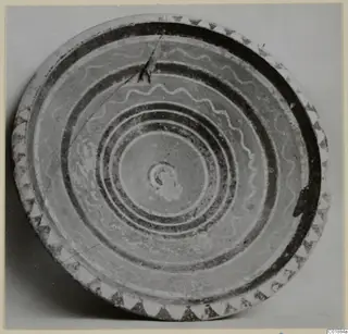 Bowl seen from above, with dark concentric bands, wavy lines across the interior and a triangle border on the rim