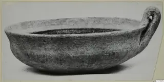 Coarse ware bowl with a single loop handle, shown from the side against a pale background.