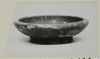 Black glazed ware bowl with a low foot, photographed on a card mount