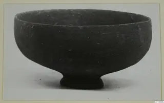 Pottery bowl with a wide rounded body and a short ring foot, photographed against a plain background.