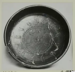 Black glazed bowl with rosette and palmette-like decoration inside, photographed from above