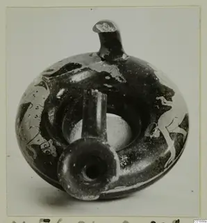Dark-glazed vessel with a flat ring-like body, a tall upright spout and a short side spout, with pale painted figures on its sides.