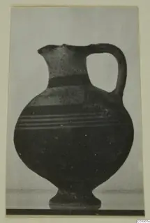 White Painted I jug with a high loop handle and a pedestal foot, photographed against a plain background