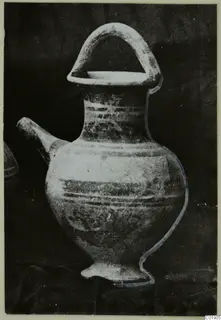 Pottery White Painted II vessel with a spout, high loop handle and painted bands, on a dark cloth
