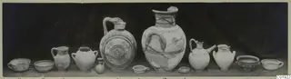 Jars and bowls from Marion, Dromos Niche, arranged in a row on a surface against a dark backdrop