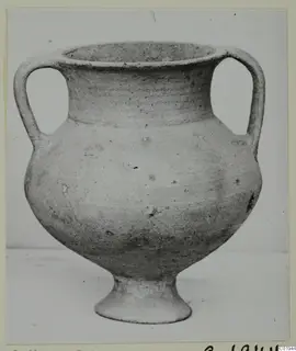 Pottery amphoriskos with two handles and a ring foot, shown against a plain background.