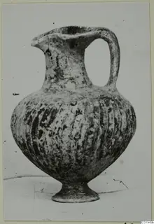 Pottery jug, Black Slip I-VI, with a strap handle, vertical fluting and a pedestal foot