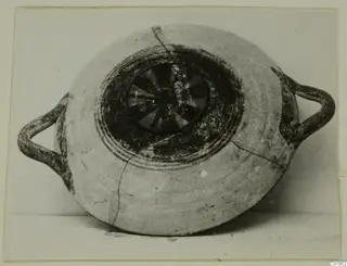 Two-handled pottery vessel from Lapithos, seen from above, with dark painted concentric rings and a radiating pattern in the centre.