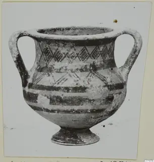 Two-handled pottery vessel with dark painted bands and diamond-shaped motifs on the body, on a short foot