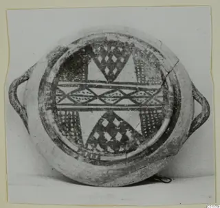 Round painted vessel with two loop handles, seen from above, decorated with dark geometric bands and diamond motifs