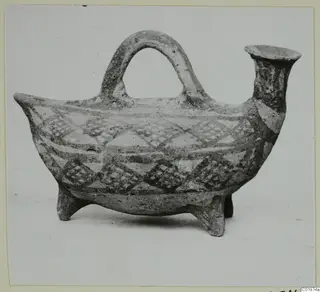 Pottery White Painted I vessel with a loop handle, spout and three legs, decorated with bands and diamond patterns.