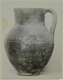 Coarse ware jug with a single handle, from the Kastros tombs at Lapithos, photographed against a plain background