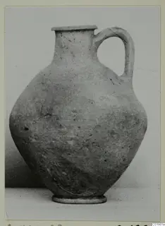 Plain pottery jug with a single loop handle, a flared rim and a rounded body on a ring foot.