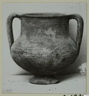 Two-handled amphoriskos on a low foot, a pottery vessel photographed against a plain background.