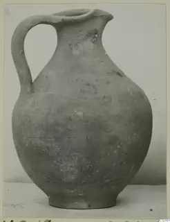 Pottery Plain White VII, a one-handled jug with a broken rim, photographed against a pale background