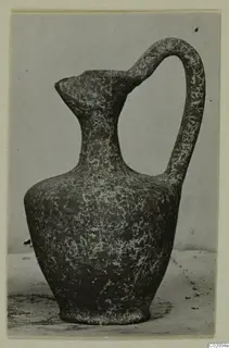 Pottery Plain White VI jug with a tall loop handle and a pointed spout, mottled dark surface