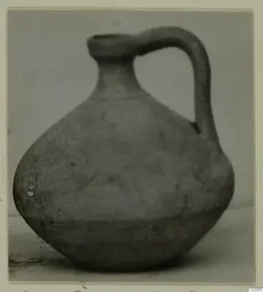 Pottery jug with a single loop handle and rounded body, photographed against a plain background.