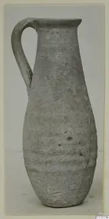 Plain pottery jug with a single loop handle and a tall, narrow neck, photographed upright on a plain background.