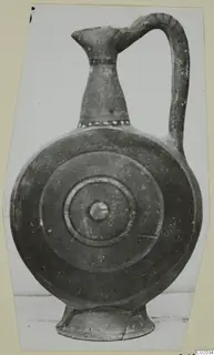 Round-bodied jug with a tall neck, strap handle and concentric rings on its front