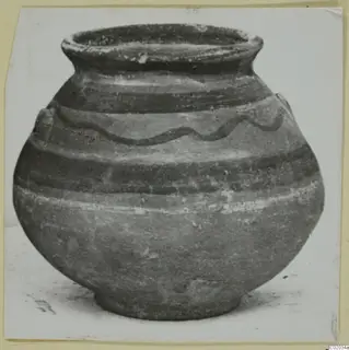 Round pottery vessel with a wide flaring rim and a dark wavy painted line around the shoulder