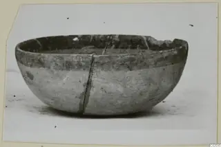 Pottery Bichrome IV bowl with a chipped rim and a long crack down its side, shown on a pale surface
