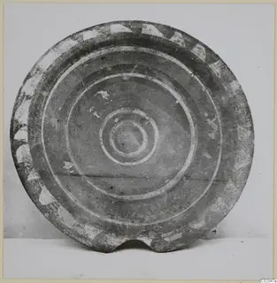 Round pottery vessel with a pale painted rim pattern and concentric circles at the centre, photographed face-on.