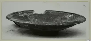 Shallow dark bowl with a broken rim and low ring foot, from Marion, shown in side view