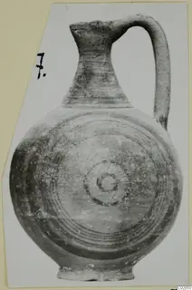 Pottery jug, Black-on-Red II-IV, with a tall neck, strap handle and concentric circles painted on its rounded body