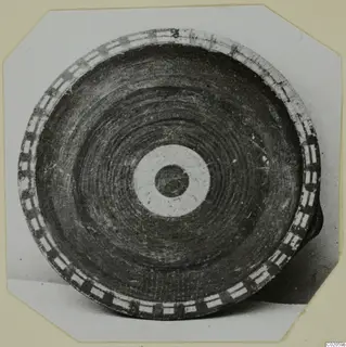Pottery vessel seen from above, with a rim band of alternating rectangles and a central pale ring with a dark disc