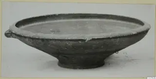 Shallow bowl with a small lug handle and a low ring foot, photographed from the side.