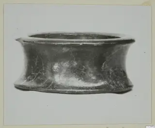 Black glazed ware bowl with a flaring rim and waisted sides, seen from the side