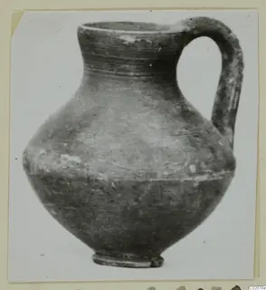 Round-bodied jug with a tall neck and a loop handle, photographed on a plain background.