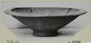 Pottery Plain White IV-V bowl with flaring sides, a thick rim and a short ring foot, seen from the side.
