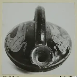 Round pottery vessel with a tall strap handle and dark glaze, with pale patterned panels on the body