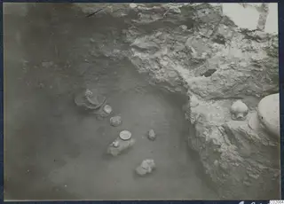Pots and a small bowl lying on the floor of an excavated area at Marion