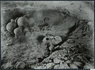 Tomb 6 at Ayios Iakovos during excavation, with several jugs, bowls and a skeleton in the chamber