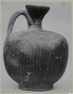 Jug of Stroke Polished Ware with a single loop handle and a flared mouth, shown against a plain background