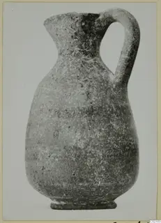 Pottery jug with a loop handle, flared mouth and ring foot, photographed against a plain pale background