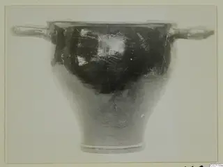 Black glazed pottery bowl with two horizontal handles and a flaring foot, seen from the side