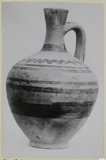 Pottery White Painted VII, a jug with a single handle and dark painted bands on a pale body
