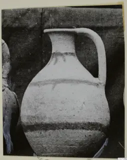 Pottery White Painted VII, a jug with a single handle and dark painted bands, photographed against a dark backdrop