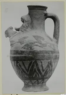 White Painted VII jug with a single handle, dark painted bands and a zigzag pattern on the body, shown on a card mount.