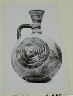 Round-bodied jug with a single handle and concentric circle decoration, photographed on a mounted card