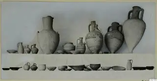 Pottery vessels from Marion Tomb 59, jugs, two-handled jars and bowls set out in two rows against a pale background.